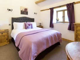 A bedroom with a bed with purple bedding and wooden furniture at Little Cow House in Pontfaen near Chirk