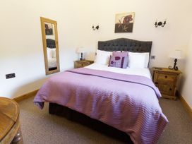 A bedroom with a double bed purple bedding wooden nightstands and a wall mirror at Little Cow House in Pontfaen near Chirk