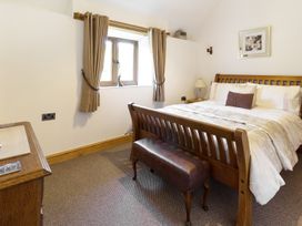 A bedroom with a wooden bed and bench near a window with curtains at Little Cow House Pontfaen near Chirk