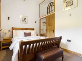A bedroom with a wooden bed white bedding a bedside table with a lamp and a wooden door at Little Cow House Pontfaen near Chirk