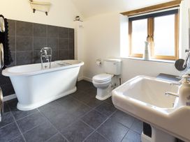 A bathroom with a freestanding bathtub toilet sink and window at Little Cow House in Pontfaen near Chirk