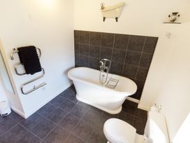A bathroom with a freestanding bathtub toilet towel rack with towel and wall decoration at Little Cow House Pontfaen near Chirk