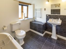 A bathroom with a toilet sink bathtub window and tiled floor at Little Cow House Pontfaen near Chirk