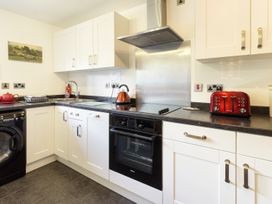 A kitchen with white cabinets a black oven a red kettle and toaster at Little Cow House in Pontfaen near Chirk