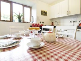 A kitchen dining area with a red and white checkered tablecloth a teapot cups and a cake on a stand at Little Cow House Pontfaen near Chirk