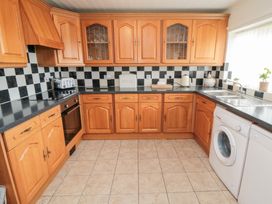 A kitchen with wood cabinets and appliances at Fairhaven Cottage, Ugthorpe near Runswick Bay