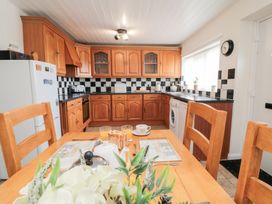 A kitchen with wooden cabinets and a dining table at Fairhaven Cottage in Ugthorpe near Runswick Bay