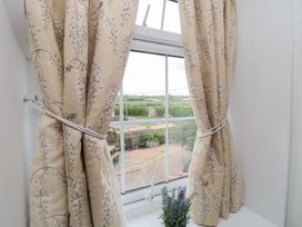 Curtains at a window with a view of a field at Fairhaven Cottage in Ugthorpe near Runswick Bay