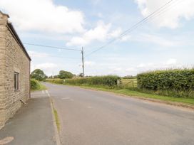 A view of a road with a stone building and hedges at Fairhaven Cottage Ugthorpe near Runswick Bay