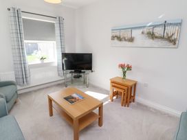 A living room with a television, sofa, and coffee table at The Haven in Embleton