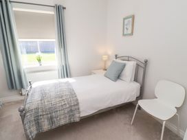 A bedroom with a bed, lamp, and chair at The Haven in Embleton