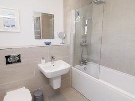 A bathroom with a shower and tub, sink, mirror, and toilet at The Haven in Embleton