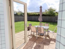 A patio with table and chairs under an umbrella at The Haven in Embleton