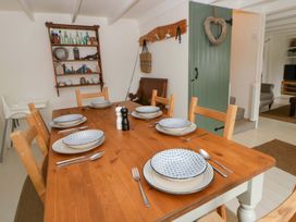 A dining room with a wooden table set for dinner at Fern Cottage in Aberporth