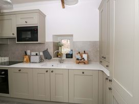 A kitchen with cabinets and appliances at Fern Cottage in Aberporth