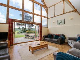 A living room with large windows and a view of outdoor seating at The Hayloft in Bleddfa near Knighton