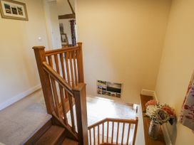 A staircase with a wooden railing in a hallway at The Hayloft Bleddfa near Knighton