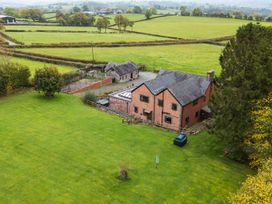 A house and outbuilding in a garden with fields in the background at Ty Newydd in Llangadfan