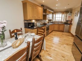 A kitchen with wooden cabinets and appliances at High Hemmel House in Embleton