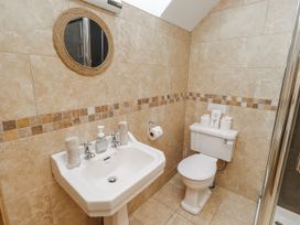 A bathroom with a sink, toilet, and mirror at High Hemmel House in Embleton