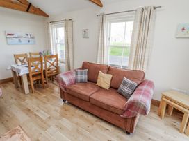 A living room with a sofa and dining area at Home Stead Cottage in Embleton