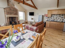 A living room with a fireplace and dining table at Home Stead Cottage in Embleton