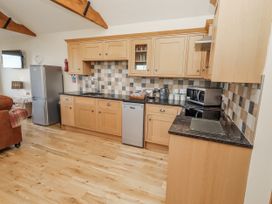 A kitchen with wooden cabinets and appliances at Home Stead Cottage Embleton