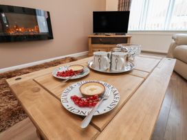 A living room with a coffee table and plates of food at La Rochelle in Whitby