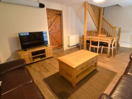 A living room featuring a sofa, coffee table, television, and dining table at Red Kite in Blaenwaun