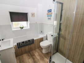 A bathroom with a bathtub, shower, sink, and toilet at Sandyhill House in Saundersfoot