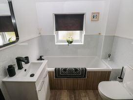A bathroom with a bath tub, sink, and toilet at Sandyhill House in Saundersfoot