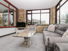 A conservatory with a sofa, coffee table and a television at Seacrest Lodge in Scarborough