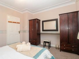 A bedroom with a bed, wardrobe, mirror, and stool at Seacrest Lodge in Scarborough