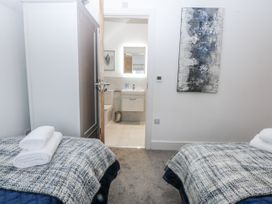 A bedroom with two beds and a bathroom visible at Estuary View in Colwyn Bay