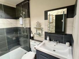 A bathroom featuring a shower, toilet, sink, and shelf at Swallows Cottage in Pembroke