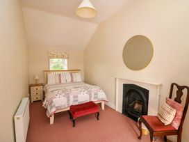 A bedroom with a bed, fireplace, and nightstand at Curradoon House, Touraneena, County Waterford