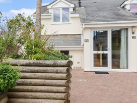 A small garden with plants in a wooden planter next to a house entrance with glass door at The Beach House in Porth near Newquay