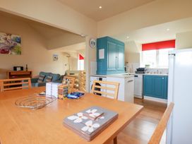A dining table with snacks and coasters in an open-plan kitchen and living area at The Beach House in Porth near Newquay