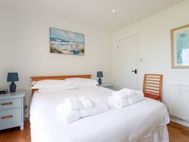 A bedroom with a bed with white linens and folded towels blue bedside tables with lamps and a wooden chair at The Beach House in Porth near Newquay