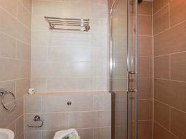 A bathroom with wall-mounted towel racks a glass shower door and a soap holder at The Beach House in Porth near Newquay