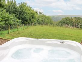 A garden with a hot tub and grass area at The Cabin in Pontardawe