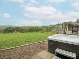 A hot tub with steps nearby and grassy area at The Cabin in Pontardawe