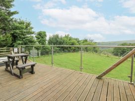 A deck with a table and bench overlooking a grassy area at The Cabin in Pontardawe