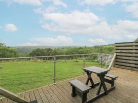 An outdoor space with a table and benches overlooking a landscape at The Cabin in Pontardawe