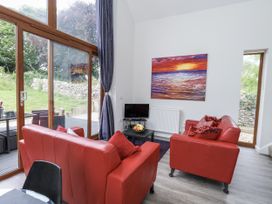 A living room with red sofas and a television at Budmouth in Upwey near Weymouth