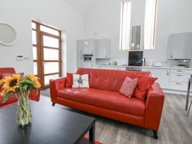 A living room with a red sofa and kitchen area at Everdene Upwey near Weymouth