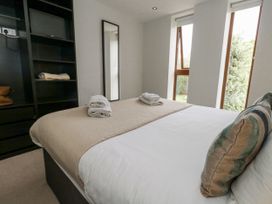 A bedroom with a bed, towels, and shelves at Everdene Upwey near Weymouth