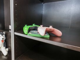 A shelf with game controllers and a plush toy at Everdene in Upwey near Weymouth