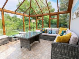 A conservatory with seating and outdoor views at Dragonfly Lodge Whinburgh near Dereham