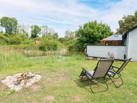 A garden with chairs and a fire pit near a pond at Dragonfly Lodge in Whinburgh near Dereham